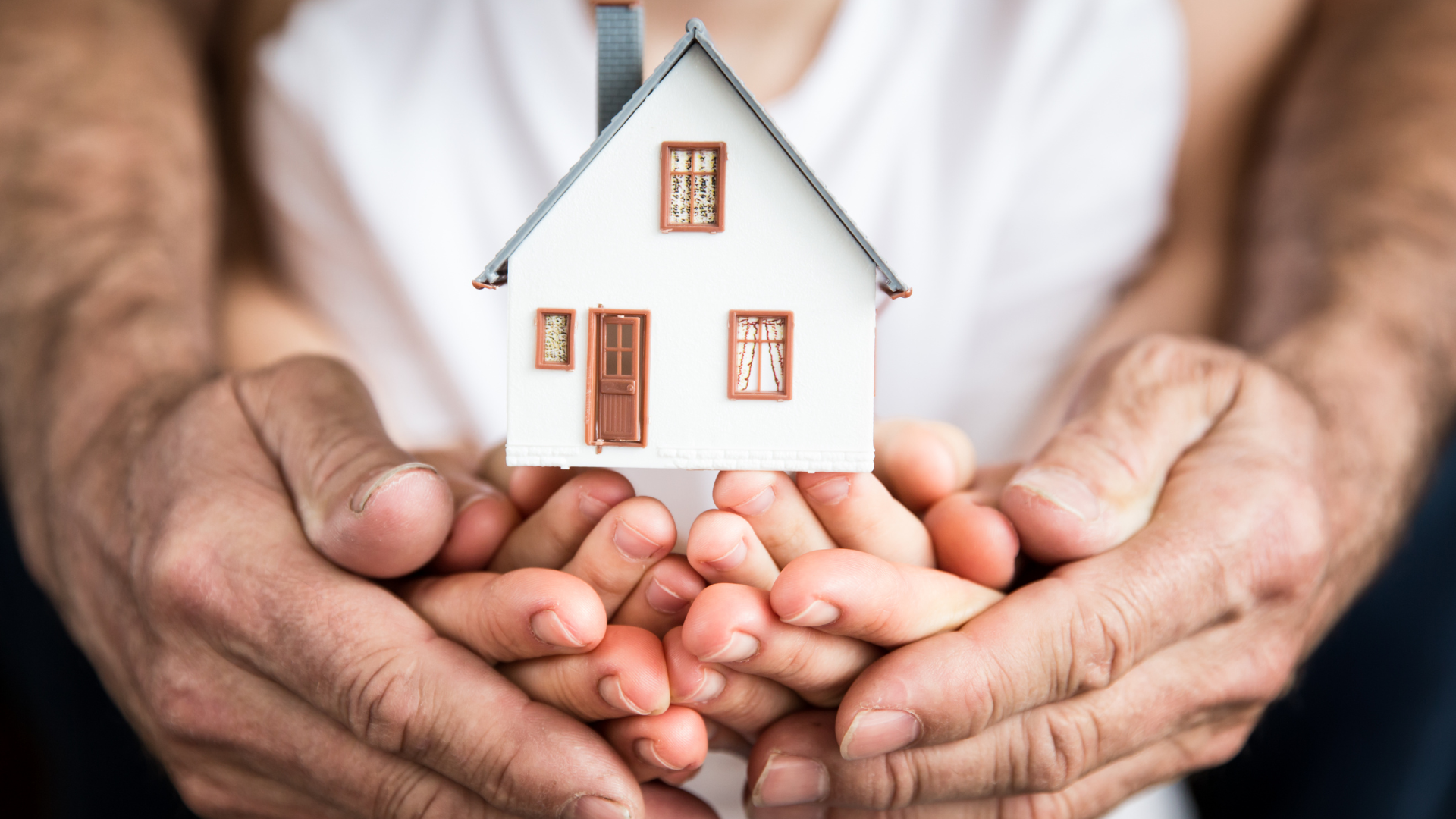 Photo d’une famille tenant une petite maison blanche entre ses mains.